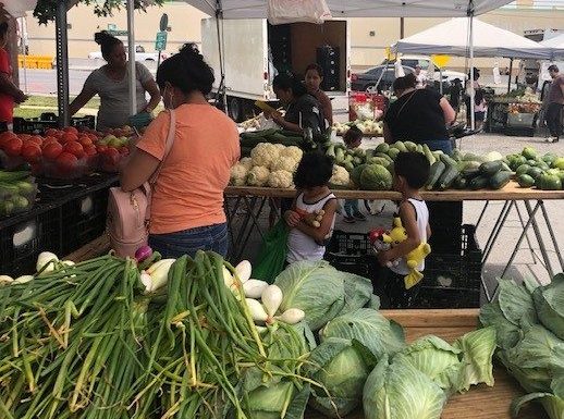 Group of people looking at produce at an outdoor farmer's market.