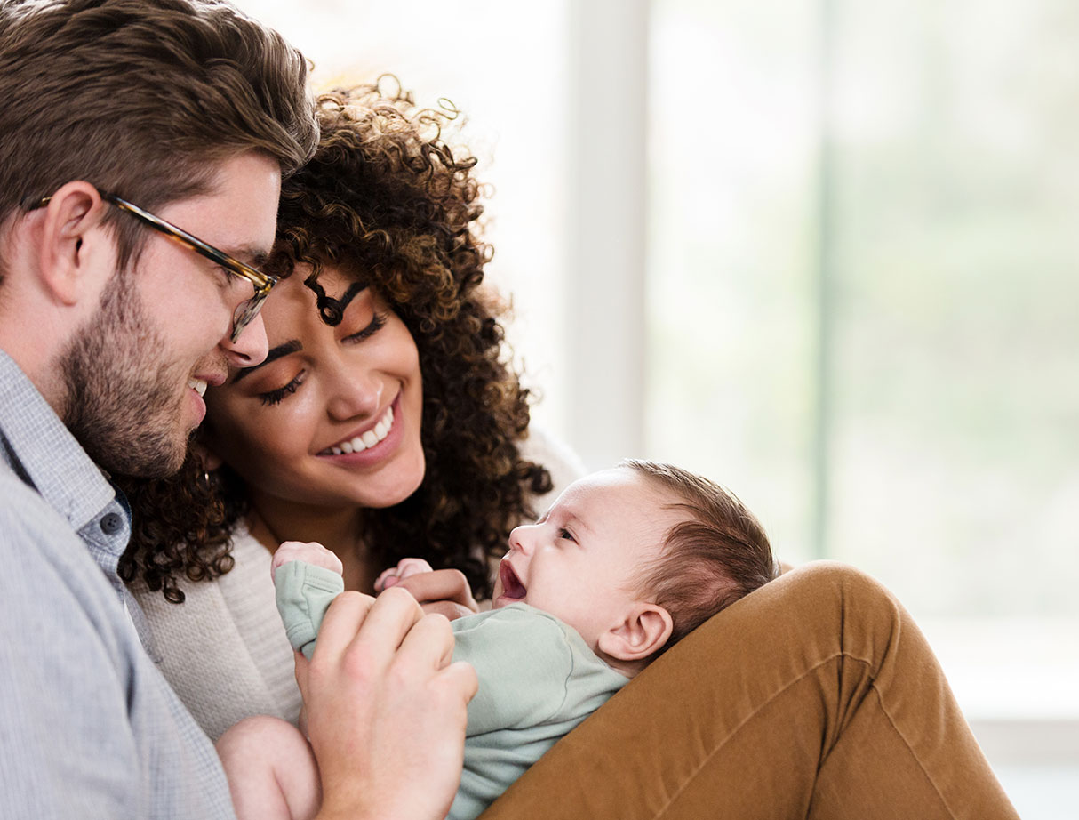 young couple holding and smiling at their newborn baby