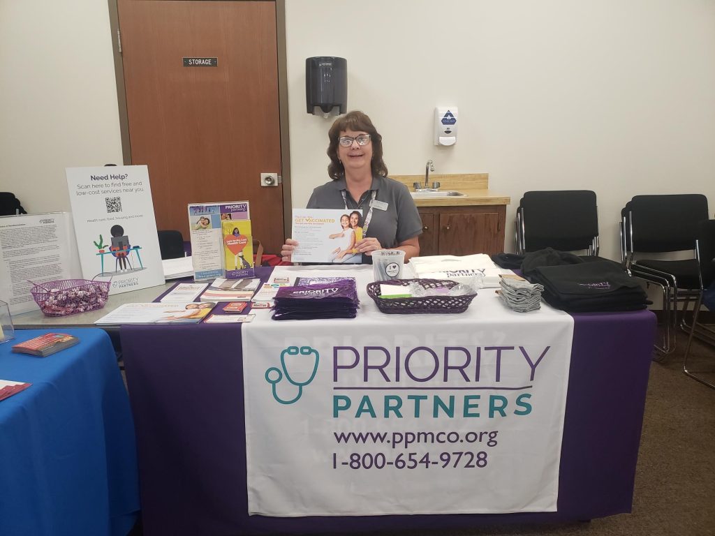 Woman sits at table with handouts about Priority Partners.