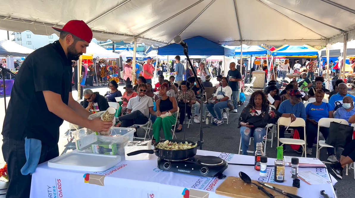 Chef Giacomo preparing for a cooking demonstration in front of sitting guests under our table tent. At the Kunta Kinte Festival