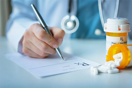 hand of a doctor writing on a prescription pad